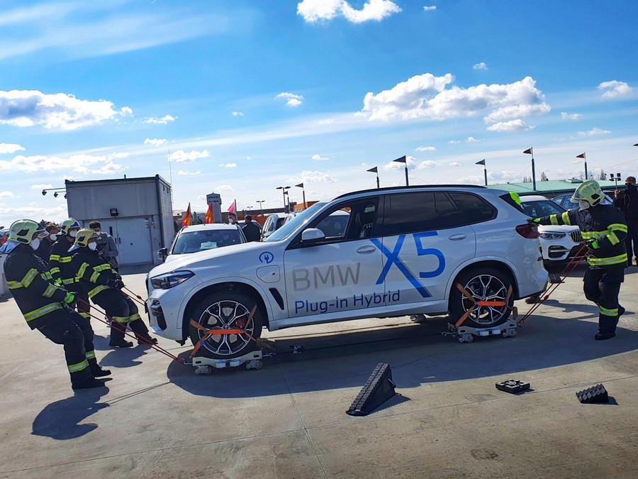 Olomoučtí hasiči vyvinuli speciální vozíky, usnadní zásah u hořícího elektromobilu Hoří automobil v podzemní garáži. Prostor se rychle plní kouřem a jedovatými zplodinami, požár ohrožuje přítomné osoby i sousední auta. To je situace, s níž se hasiči setkávají běžně. A umějí si s ní díky dobře zavedeným a prověřeným postupům poradit. Co když zde ale dojde k požáru vozidla na elektrický, nebo hybridní pohon? Zapouzdřené baterie uvnitř vozu podle zkušeností ze světa i Česka představují komplikaci při hašení. A to zejména proto, že k vývoji tepla a zplodin hoření dochází uvnitř skrytého a nedostupného akumulátoru. Jak tedy efektivně zvládnout takovou situaci? S řešením nyní přišli hasiči z HZS Olomouckého kraje, kteří vyvinuli ve spolupráci se soukromou strojírenskou společností speciální sadu technických prostředků pro manipulaci s vozidly. V podstatě se jedná o soubor unikátních pojízdných vozíků (obr. 1). Na ně se částečně uhašený vůz naloží a vyveze se z ohroženého prostoru na volné prostranství, kde se poté může bezpečně pokračovat v jeho ochlazování a hasebním zásahu. Sada pro manipulaci s vozidly slouží především k evakuaci nepojízdných automobilů a lehkých užitkových vozů o okamžité hmotnosti kolem 4 000 kilogramů tam, kde je výškově či jinak omezený přístup těžké techniky a odtahové služby. Jedná se tak hlavně o podzemní garáže, vícepodlažní parkovací objekty, parkovací domy či střešní parkoviště s plošinovými autovýtahy. Nespornou výhodou je, že můžeme díky těmto technickým prostředkům pohybovat i s automobily uzamčenými, poškozenými a nepojízdnými. Zároveň však v případě použití manipulačních vozíků nedochází k sekundárním škodám. „Tak, jak se nové technologie vyvíjejí a zavádějí do provozu, musíme na tuto situaci reagovat. Čeští hasiči jsou známí svojí flexibilitou a schopností operativně reagovat na nastalou situaci. U zásahů musíme umět správně používat stávající vybavení, jsem ale rád, že u našeho sboru máme i kolegy, kteří se podílí na vývoji a testování nových prostředků, které pomohou dalším hasičům plnit jejich poslání a možná přispějí též k jejich bezpečnosti,“ popisuje Petr Ošlejšek, náměstek ředitele pro IZS a operační řízení HZS Olomouckého kraje. Technické prostředky vyvinuli hasiči ve spolupráci se soukromou společností, s níž museli při konstrukci vozíků vyřešit hned několik problémů. Při podrobném průzkumu trhu totiž zjistili, že transportní vozíky sice již existují, používají se však pouze na konkrétní typ převozu, například v autodílnách nebo showroomech. Tento typ nebyl z mnoha důvodů pro hasičské účely vhodný (váhové limity, překážky, zpomalovací prahy, nájezdové rampy, výškové rozdíly atd.). Proto byl vyvinut nový, jehož konstrukce je velmi pevná a odolá i méně šetrnému zacházení, kterému se u zásahu mnohdy není možné vyhnout. Velkou výhodou je transport vozu samotnými hasiči, ale i vlečným, popřípadě brzdným automobilem. Po výrobě prototypu jsme přistoupili ke zkouškám manipulační sady a několika zdokonalovacím úpravám. Kromě 4 ocelových vozíků je sada opatřena vázacími prvky pro uchycení kol i jednotlivých vozíků mezi sebou. Součástí jsou též prvky pro vlečení, brždění a stabilizaci vozidla a pneumatické zvedáky. „Na vývoji pracujeme od roku 2019. První prototypy vozíků byly na světě už v lednu 2020. Během loňska jsme uskutečnili asi 13 praktických zkoušek, díky nimž jsme vozíky i celou sadu odladili. Oceňuji především spolupráci mezi hasiči a konstruktéry ze soukromé firmy. Po tak dlouhé cestě plné zkoušek konečně můžeme říct, ano, umíme…,“ vysvětluje proces vývoje nových technických prostředků Pavel Thin, velitel čety olomoucké stanice, který vedl projekční tým. Díky spolupráci se soukromými subjekty jsme mohli provádět zkoušky manipulační sady v různých typech objektů. Testy jsme uskutečnili například v podzemních garážích olomoucké Galerie Šantovka, v multifunkčním domě Namiro či ve vícepodlažních parkovacích domech autosalonů v Olomouci (obr. 2). Místa testů jsme nevolili náhodně. Vybírali jsme ta, která svou dispozicí mohou potrápit nejen řidiče v běžném životě, ale při zásahu i hasiče. Otestovali jsme vozíky rovněž na příčných prazích, na šikmých rampách, v autovýtazích nebo v podzemních garážích s komplikovaným nájezdem i výjezdem. Manipulovali jsme jak s běžnými vozidly, tak také s automobily na hybridní nebo alternativní pohony. Sadu budeme přepravovat na místo zásahu na přívěsném vozíku, aby ji bylo možné využít operativně. Nyní bude umístěna na centrální stanici v Olomouci, využít při zásahu ji však bude možné kdekoli v Olomouckém kraji. Sada pro manipulaci s vozidly byla částečně financována z daru generálního partnera projektu Galerie Šantovka Olomouc a částečně z prostředků HZS Olomouckého kraje. Na jejím vývoji se konstrukčně podílela společnost Přidal s.r.o., která manipulační vozíky též vyrobila. Taktiku nasazení a širší využití technických prostředků jsme konzultovali s Generálním ředitelstvím HZS ČR, technické parametry jsme ověřovali ve spolupráci s Technickým ústavem požární ochrany GŘ HZS ČR. Testování v reálném provozu jsme mohli uskutečnit díky spolupráci s Českou asociací hasičských důstojníků, s Lukášem Hatašem, výkonným ředitelem Asociace pro elektromobilitu České republiky, Magistrátem města Olomouce a olomouckými autosalony Samohýl Motor, Centrum-Moravia Olomouc a CarTec Olomouc. Mgr